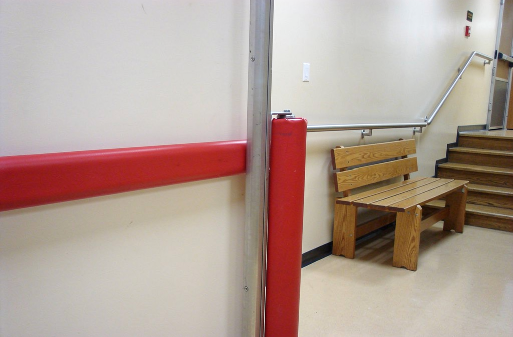 Protection murale PVC rouge installée le long d'un poteau dans un couloir d'hôpital