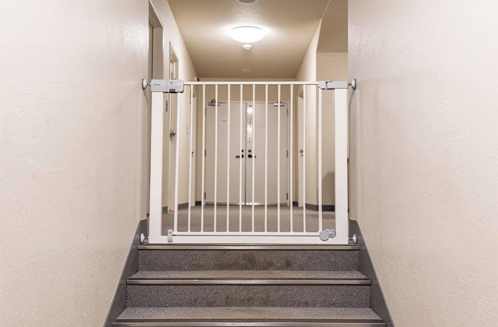 Barrière de sécurité blanche installée en haut d'un escalier dans les parties communes d'un immeuble collectif bien éclairé.