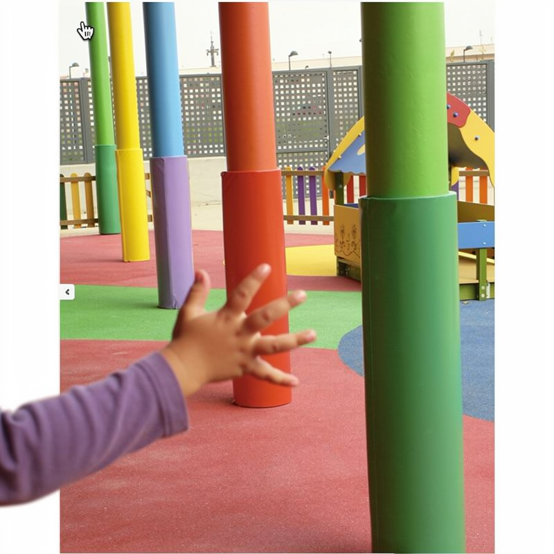 Revêtements de protection en mousse haute densité colorés installés sur des poteaux dans une aire de jeux pour enfants.