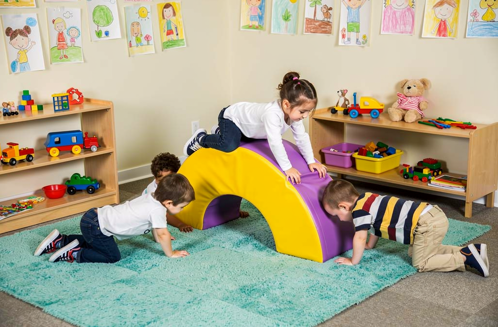 Arc de motricité en mousse utilisé par des enfants en maternelle pour développer l'équilibre.