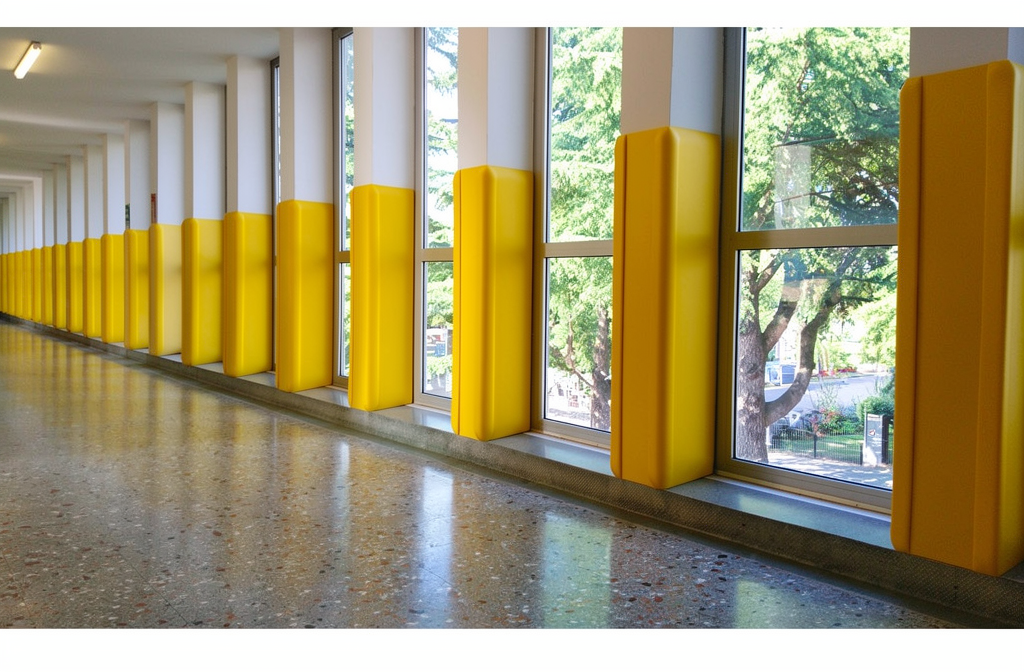 Cornières de protection d'angle jaunes installées sur des colonnes dans un couloir commercial.