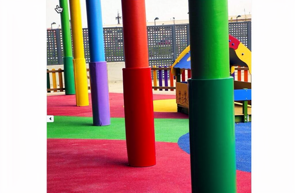 Poteaux cylindriques colorés installés sur un sol de sécurité dans une aire de jeux extérieure conforme.