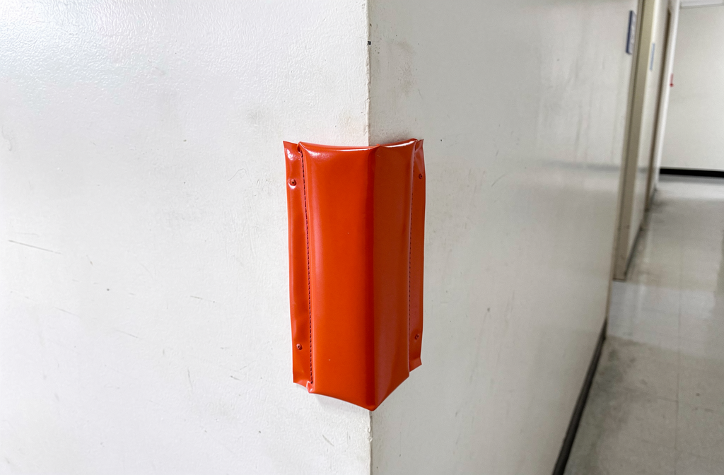 Protection d'angle orange installée sur un coin de mur blanc dans un couloir