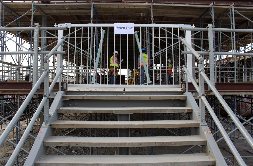 Barrière de sécurité blanche installée en haut d'un escalier de chantier.