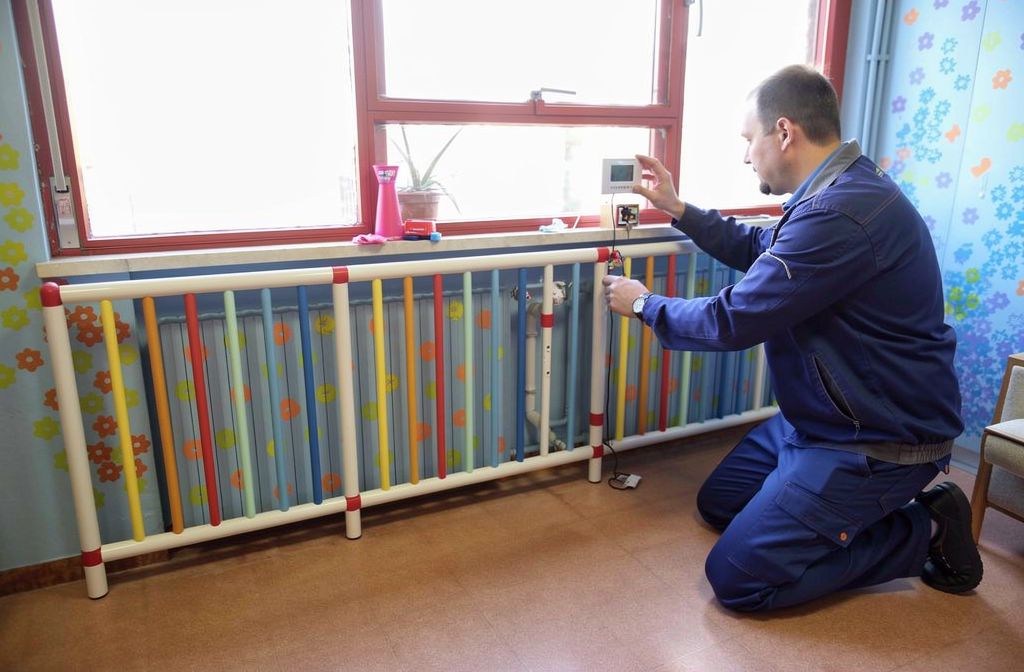 Grille de protection de radiateur colorée installée devant un radiateur mural dans une pièce lumineuse.