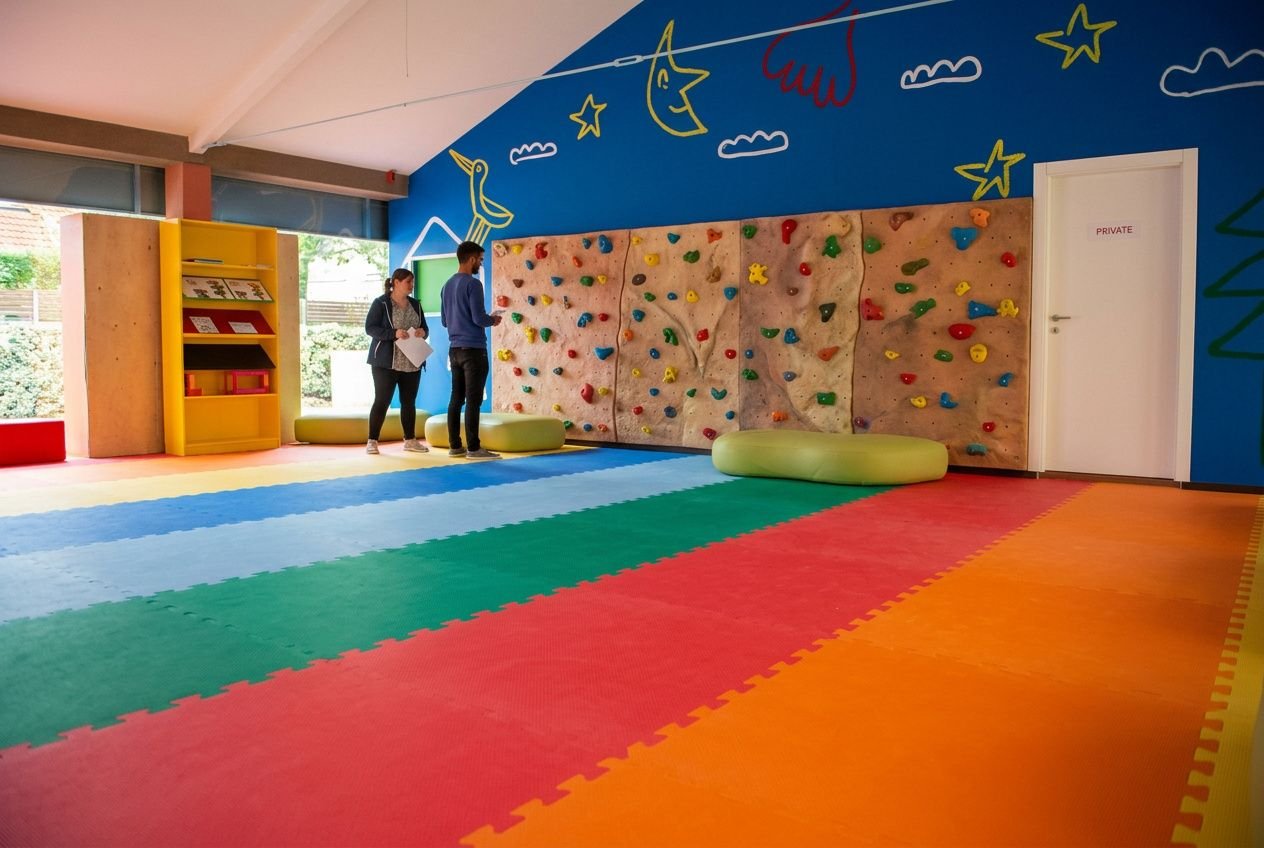Hauteur mur de bloc : mur d’escalade intérieur avec mur d’escalade en blocs et tapis colorés, deux personnes vérifiant la zone sécurité.