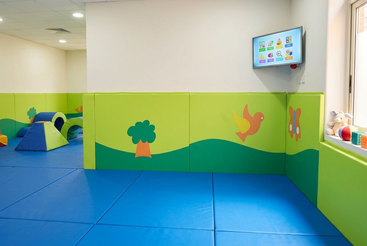 Panneaux muraux de protection colorés et mousse, fond mural vert et bleu avec décor d’arbres et d’animaux dans un gymnase d’enfants. Site pour protéger murs gymnase.